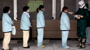 Pessoas fazem fila para triagem de radiação na prefeitura de Fukushima 