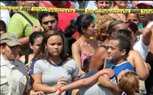 Homem socorre uma jovem que desmaiou ao procurar um familiar em meio aos feridos