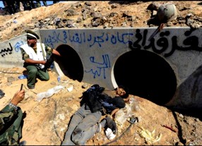 Rebeldes do governo interino líbio mostram túnel onde Muammar Khadafi supostamente foi capturado. O grafite em azul diz: "Este é o lugar de Khadafi, o rato... Deus é maior" Rebeldes do governo interino líbio mostram túnel onde Muammar Khadafi supostamente foi capturado. O grafite em azul diz: "Este é o lugar de Khadafi, o rato... Deus é maior"