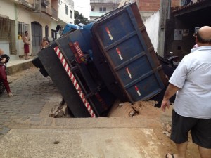 Caminhão servindo a Prefeitura afunda em canaleta e cobre motocicleta com asfalto