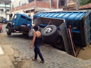 Caminhão servindo a Prefeitura afunda em canaleta e cobre motocicleta com asfalto